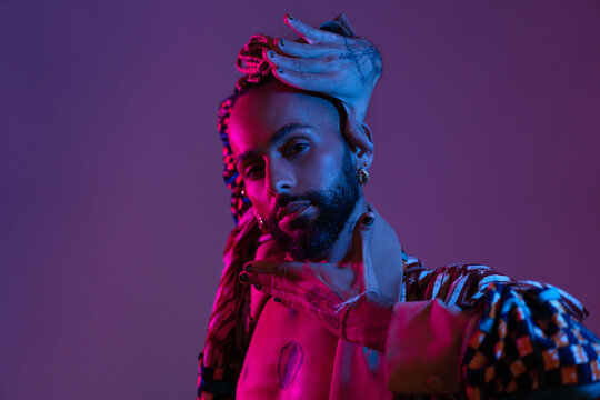 Retro wave or synth wave portrait stylish serious african-american dancer man studio shoot. High Fashion male model dance in colorful bright neon lights posing.