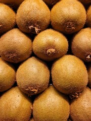 Stacked kiwis forming a fresh and vibrant background. The image highlights the natural texture and earthy tones of the fruit, ideal for healthy food concepts, packaging design, or organic lifestyle.