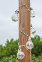 A string of LED bulbs hanging from a wooden post