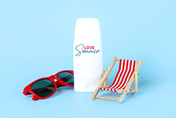 Closeup of red sunglasses, beach deck chair and bottle of sunscreen with love summer written on it. Summer vacation concept
