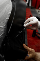 Vinyl wrap installation on car with precise edge trimming near windshield area. Vinyl wrap installation on car with careful edge cut. Wrapping technician smooths and cuts vinyl wrap on car.