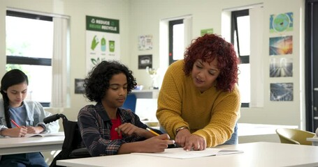 Female teacher helping boy in wheelchair with writing in classroom, fostering learning, at school - Powered by Adobe