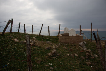 graves on a coastal hill enclosed by rustic barbed fence