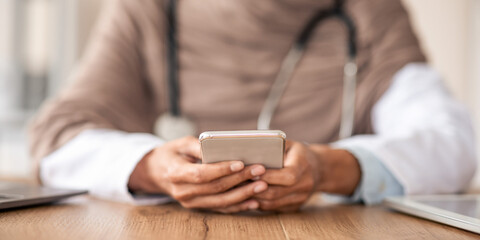 Modern technologies in healthcare. Cropped of female doctor sitting in her cabinet, using mobile phone. Unrecognizable muslim woman physician working online from clinic, using application