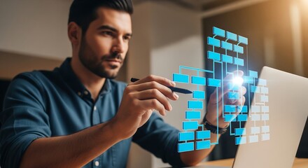 Man in blue shirt using a pen to interact with a virtual flowchart displayed near a laptop. Focused expression. Modern workspace.