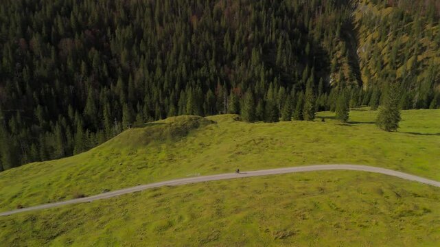 Aerial view of cyclist on gravel bike touring through Valepp Valley, Bavaria, Germany. Surrounded by Schlierseer and Mangfall Mountains, this scenic autumn ride embodies adventure and exploration. 