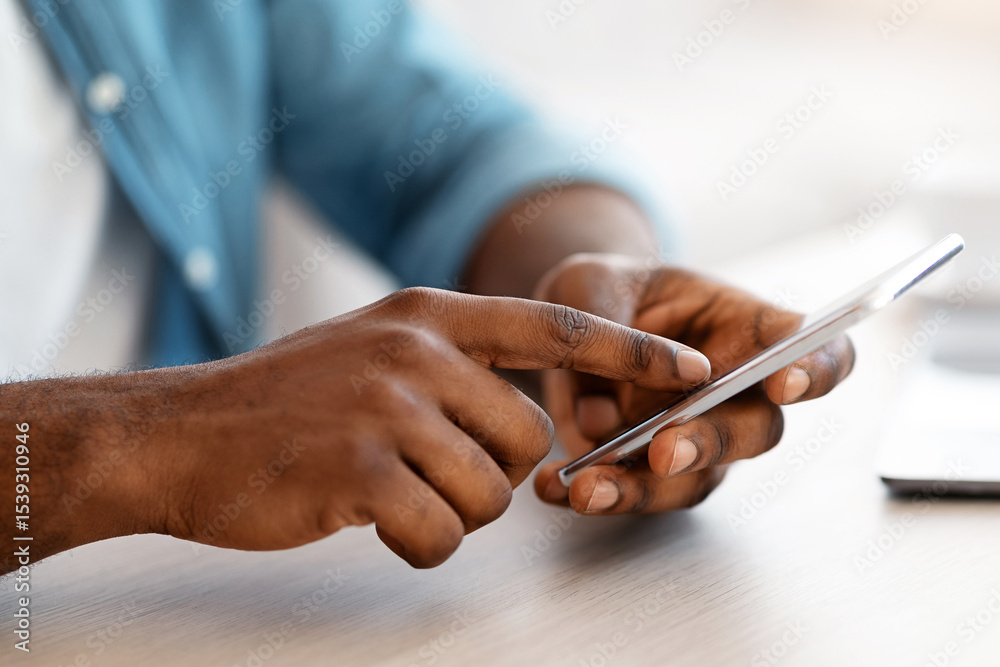 Poster cropped image of unrecognizable black man using smartphone while sitting at desk in office, african 