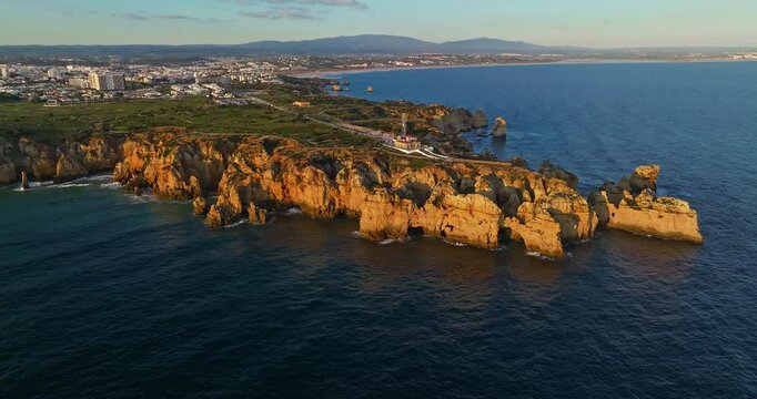 Aerial view of the Ponta da Piedade lighthouse surrounded by cliffs, boats, and turquoise water in Lagos, Portugal