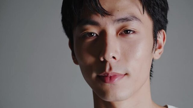 Japanese man with confident smirk exhaling slowly under ring light