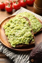 Delicious sandwiches with avocado, sesame seeds and tomatoes on wooden table, closeup