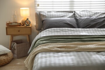 Comfortable bed with soft linens and blankets in room, closeup. Home textile