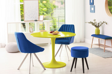 Yellow dining table and blue chairs in room. Interior design