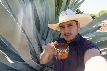 Mexican man enjoys pulque next to large agave plant in rural Mexico