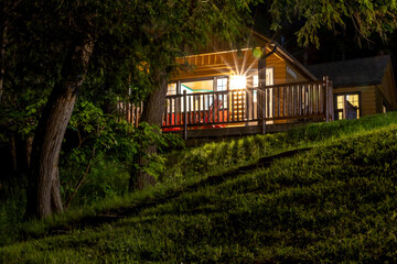 A cozy and illuminated cabin nestled in the woods at Cedar Grove Lodge, Huntsville, offering a peaceful night retreat.