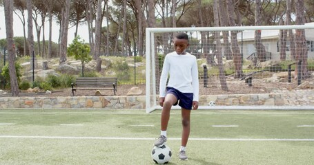 african american boy playing soccer on field, confidently standing with ball, copy space