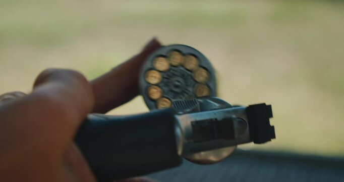 Close-up view of a revolver cylinder loaded with bullets held outdoors on shooting range, focused on the ammunition and bullets