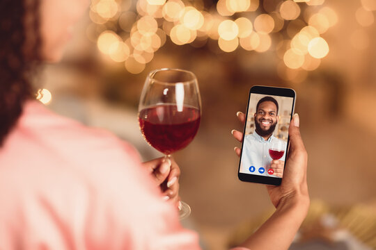 Online Date, Safe Meeting With Friends. Over The Shoulder Back View Of African American Woman Talking By Video Chat To Her Boyfriend Using Smartphone And Drinking Red Wine. Stay Home. Social Distance.