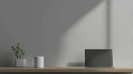 Minimalist modern workspace with a sleek laptop, potted plant, and ceramic mug on a wooden desk against a plain gray wall with natural light