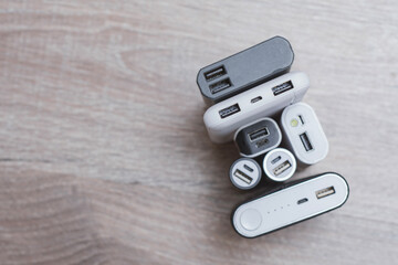 Assortment of portable power banks in various designs on a wooden surface. Portable chargers for...