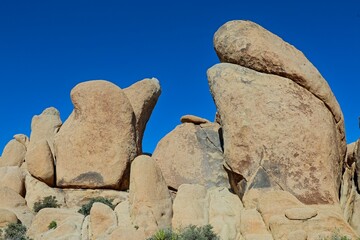 Interesting rock formations and stacks of boulders bake in the desert sun in California's Joshua...