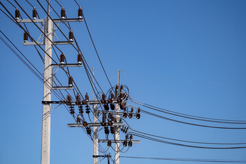 High voltage transmission pole with electrical equipment including cables and insulators on concrete structure under clear blue sky showing modern power grid infrastructure in wind energy facility