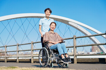 車椅子に乗った中年の女性と介護士　屋外　ポートレート　カメラ目線