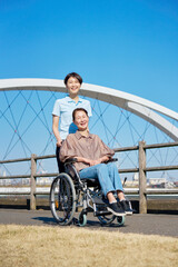 車椅子に乗った中年の女性と介護士　屋外　ポートレート　カメラ目線