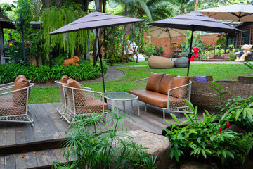 Outdoor seating area with wicker chairs and umbrellas in lush garden setting