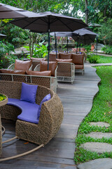 Outdoor seating area with wicker furniture and umbrellas on wooden deck in lush garden setting