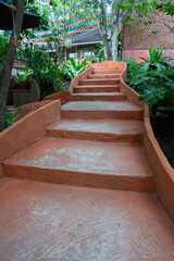 Curved orange concrete steps lead through lush greenery in garden setting