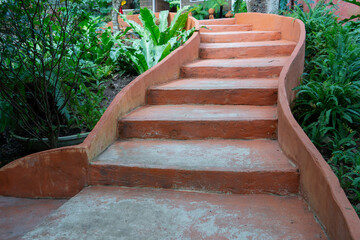 Curved orange concrete steps lead through lush garden with green foliage