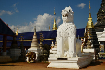 Statues of white Singha, which are animals in Thai art, decorate the front of the pagoda at Wat Den...