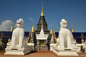 Statues of white Singha, which are animals in Thai art, decorate the front of the pagoda at Wat Den...