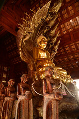 Golden sitting Buddha statue and there is a serpent covering the back in Buddhist Thai Church at Wat Den Sali Si Mueang Kaen temple. Located at Chiang Mai city in Thailand.