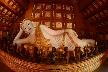 The Reclining white statue Buddha is enshrined in a teakwood chapel at Wat Den Sali Si Mueang Kaen temple or Wat Ban Den. Located at Cheng Mai Province in Thailand.