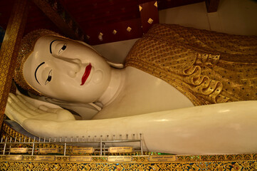 The Reclining white statue Phra Chaeo Nip Phran Buddha is enshrined in a teakwood chapel at Wat Den Sali Si Mueang Kaen temple or Wat Ban Den. Located at Cheng Mai Province in Thailand.