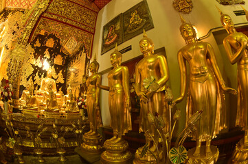 Group of standing Buddha front of golden sitting statue of Phra Kaew Klao Chao Bun Rueang Buddha is enshrined in a church at Wat Den Sali Si Mueang Kaen temple or Wat Ban Den. At Chiang Mai , Thailand