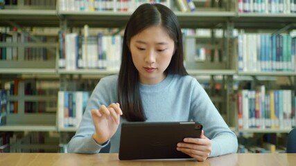 Focused student navigating digital learning on a tablet in a tranquil library - Powered by Adobe