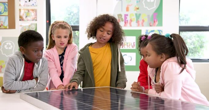 School children exploring solar panel in classroom, learning about renewable energy