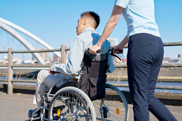 介護士が押す車椅子に乗るシニア男性