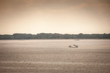A lone work boat crosses the broad Danube near Serbia's forested shoreline beneath a warm, hazy...