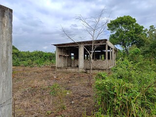 Abandoned unfinished concrete house in rural Guatemala surrounded by vegetation