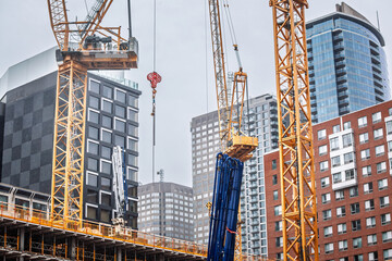 Tower cranes lift heavy sections on a new high rise build in downtown Montreal while existing condo...