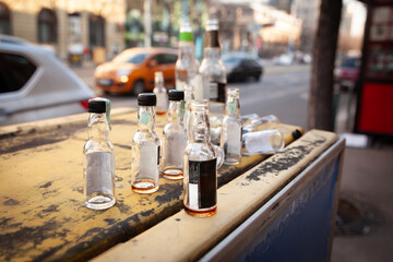 Small liquor bottles with traces of spirit litter a counter on Budapest boulevard, Selective blur on empty miniature alcohol bottles scattered in a street of budapest after hunge binge drinking party.