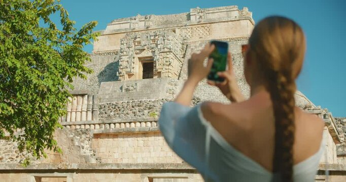Close-up of woman photographing ancient Mayan ruins architecture in Mexico