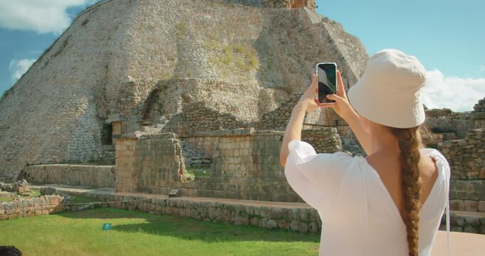 Tourist photographing the Pyramid of the Magician at Uxmal during trip in Mexico