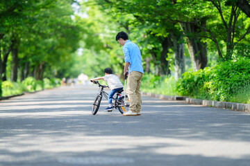 Fototapeta premium 自転車の練習をする5歳の男の子とフォローする父親