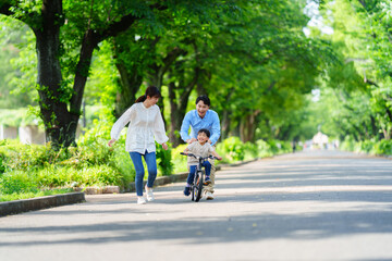 両親と自転車の練習をする5歳の少年