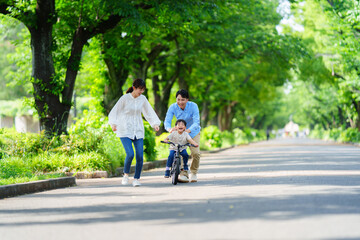 両親と自転車の練習をする5歳の少年
