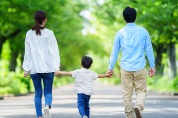 手を繋いで歩く家族の後ろ姿